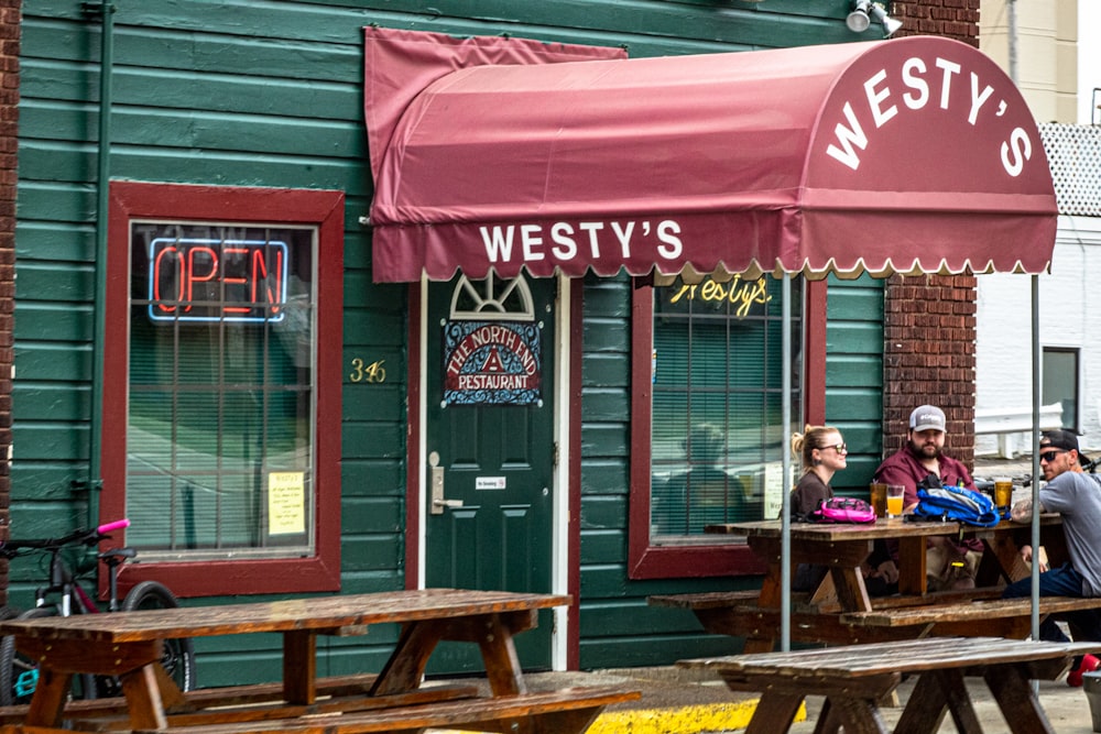 trois personnes s’assoient sur une table de pique-à l’extérieur du restaurant Westy’s