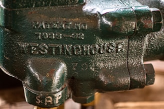 A close-up view of a green metallic component with inscriptions including 'WESTINGHOUSE' and a patent number. The surface has a textured finish with visible bolts.