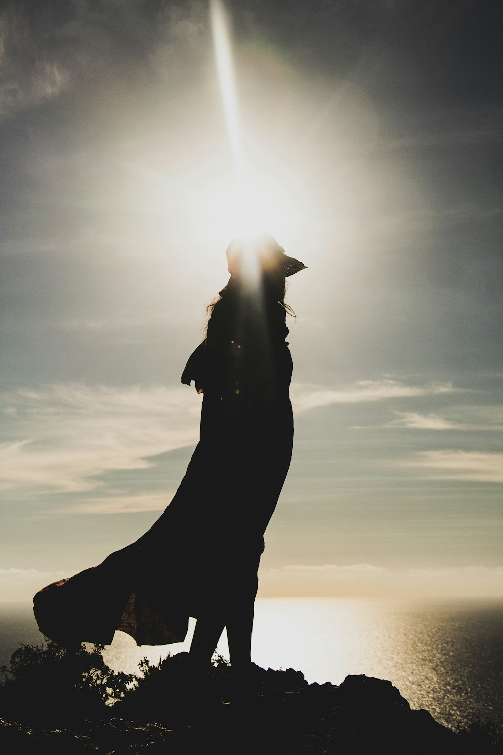 silhouette of woman in dress near cliff photo