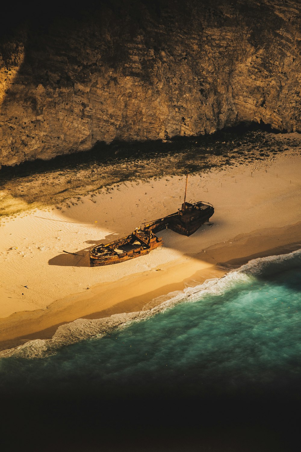 wrecked and abandoned ship on shore of an island during golden hour