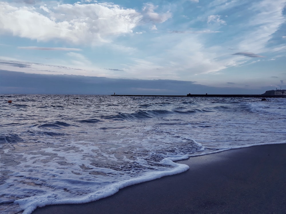 schiuma di mare sulla riva durante il giorno
