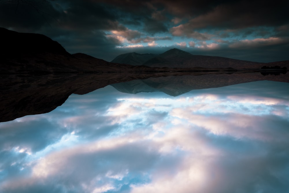 reflection of dramatic clouds on calm body of water