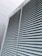 A large industrial vent is featured prominently, with horizontal metal slats covering its entirety. The structure appears to be part of a building exterior, with visible weathering and discoloration on the surfaces.