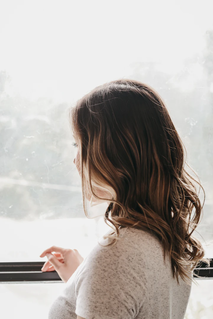 Woman standing and looking out through a glass window
