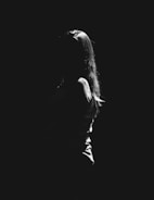 Silhouetted figure standing against a black background with subtle highlights.