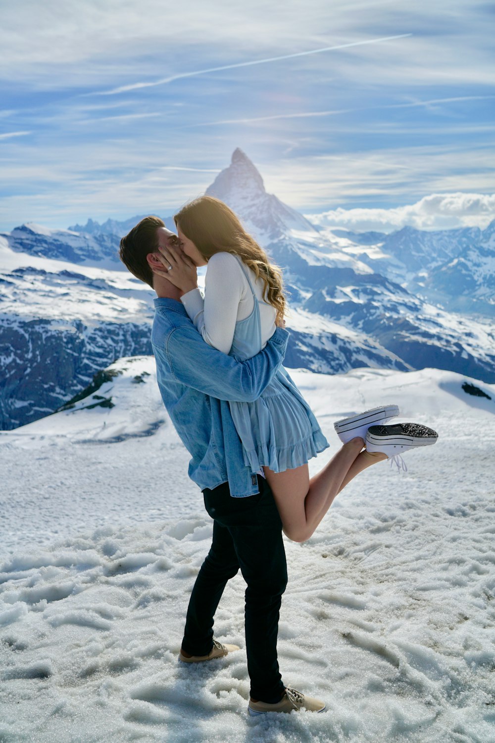 uomo che trasporta la donna e bacia sotto il cielo blu chiaro