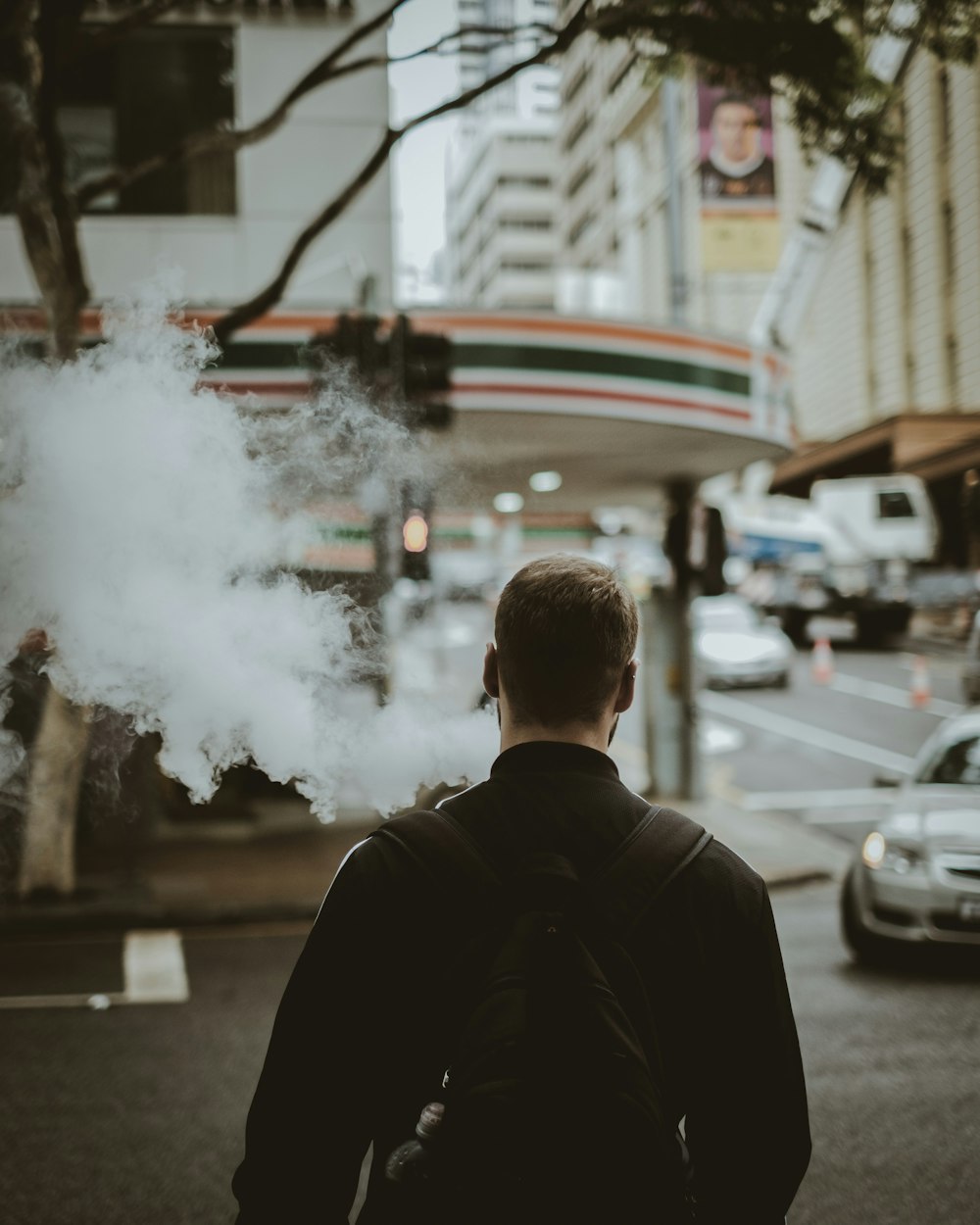 man about to cross road while smoking during daytime