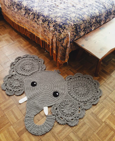 black and gray elephant plush toy on brown wooden table