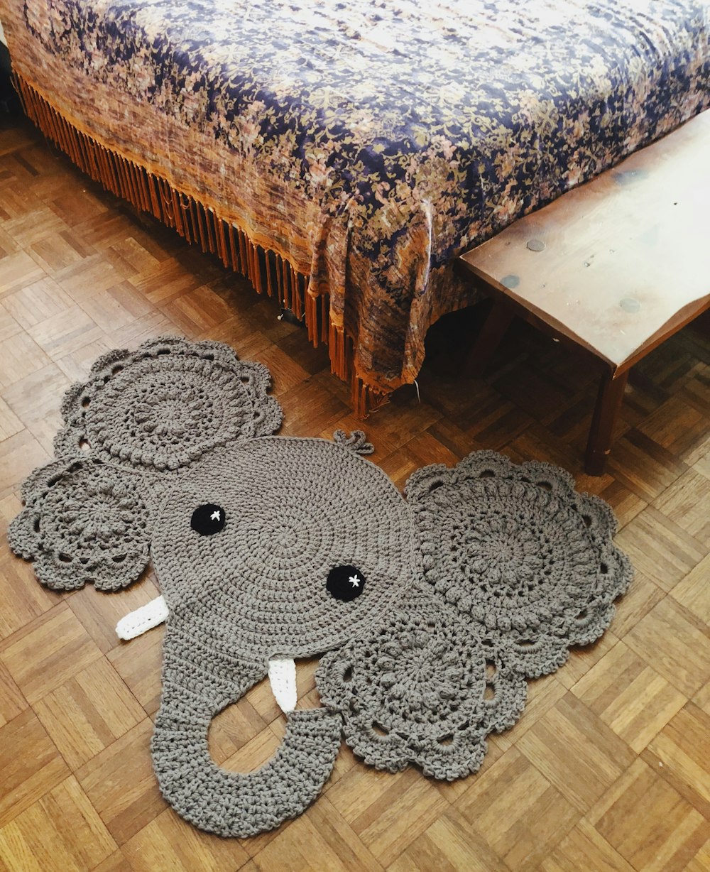 black and gray elephant plush toy on brown wooden table