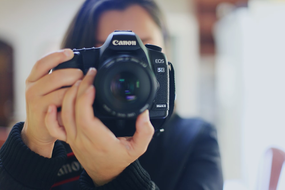 woman using black Canon DSLR camera