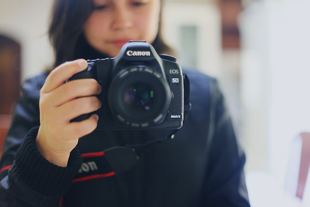 person holding black Canon DSLR camera