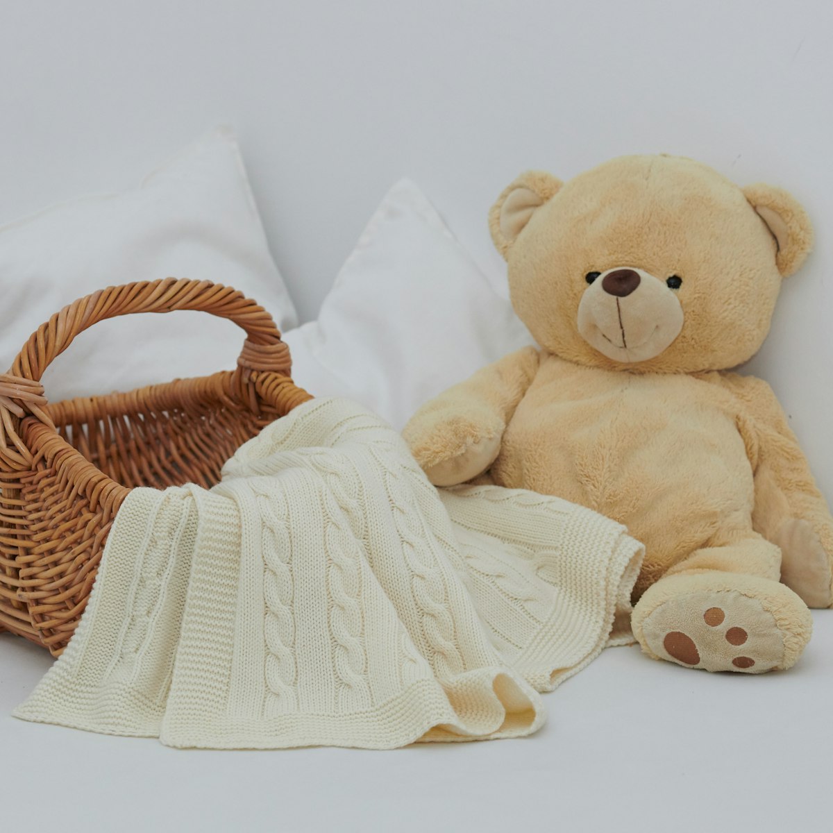 Cream keepsake plushie tucked in a soft knit blanket and basket