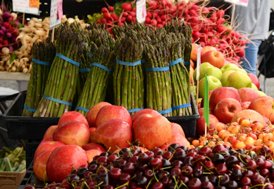 Close-up of a vibrant, fresh market display featuring local produce with matte forest green and deep crimson tones.