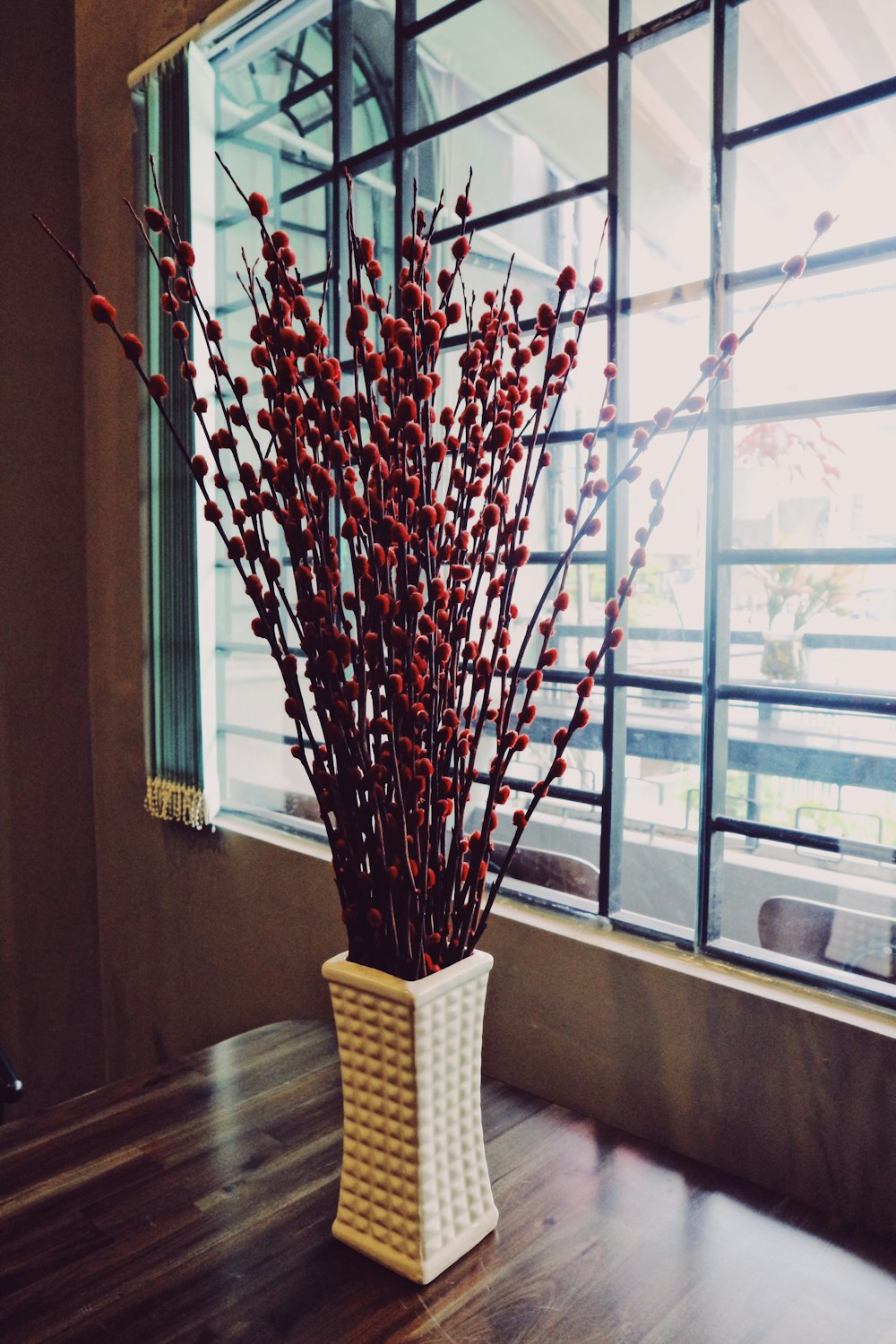 a vase filled with red flowers on top of a wooden table