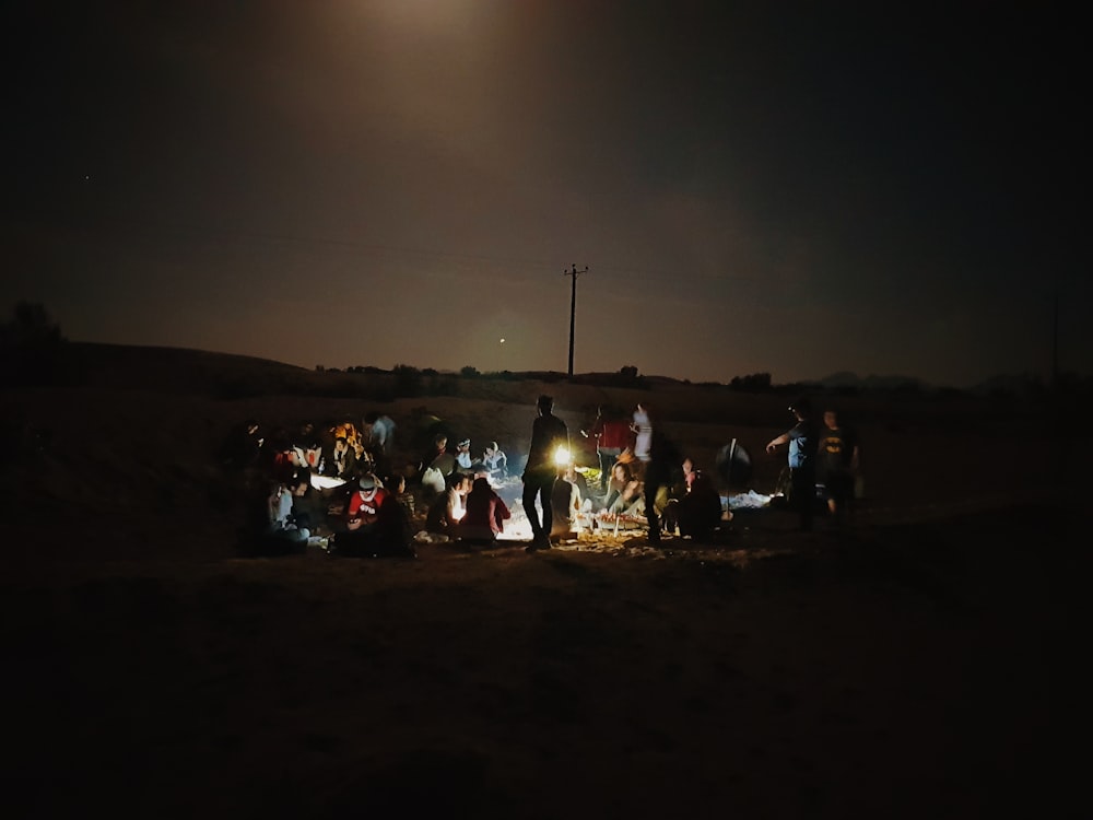 a group of people sitting around a campfire at night