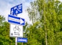 blue and white signage near trees during daytime
