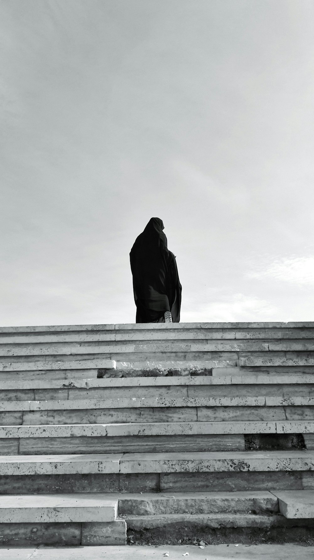 ein Schwarz-Weiß-Foto einer Person, die auf einigen Stufen sitzt