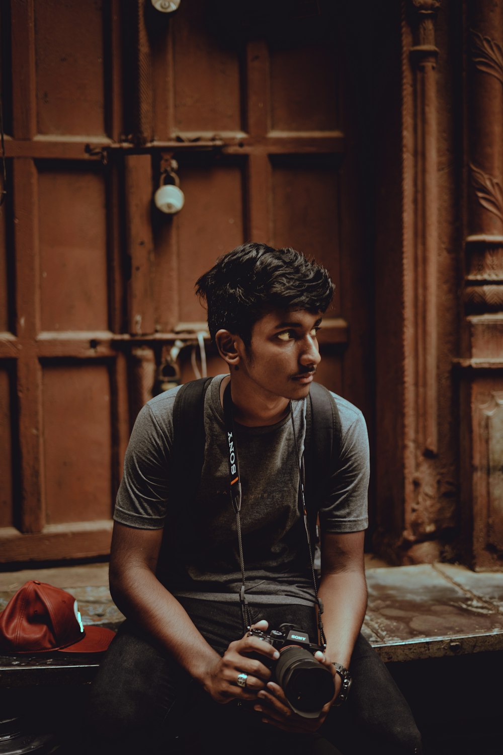 man sitting in front of closed door holding black camera