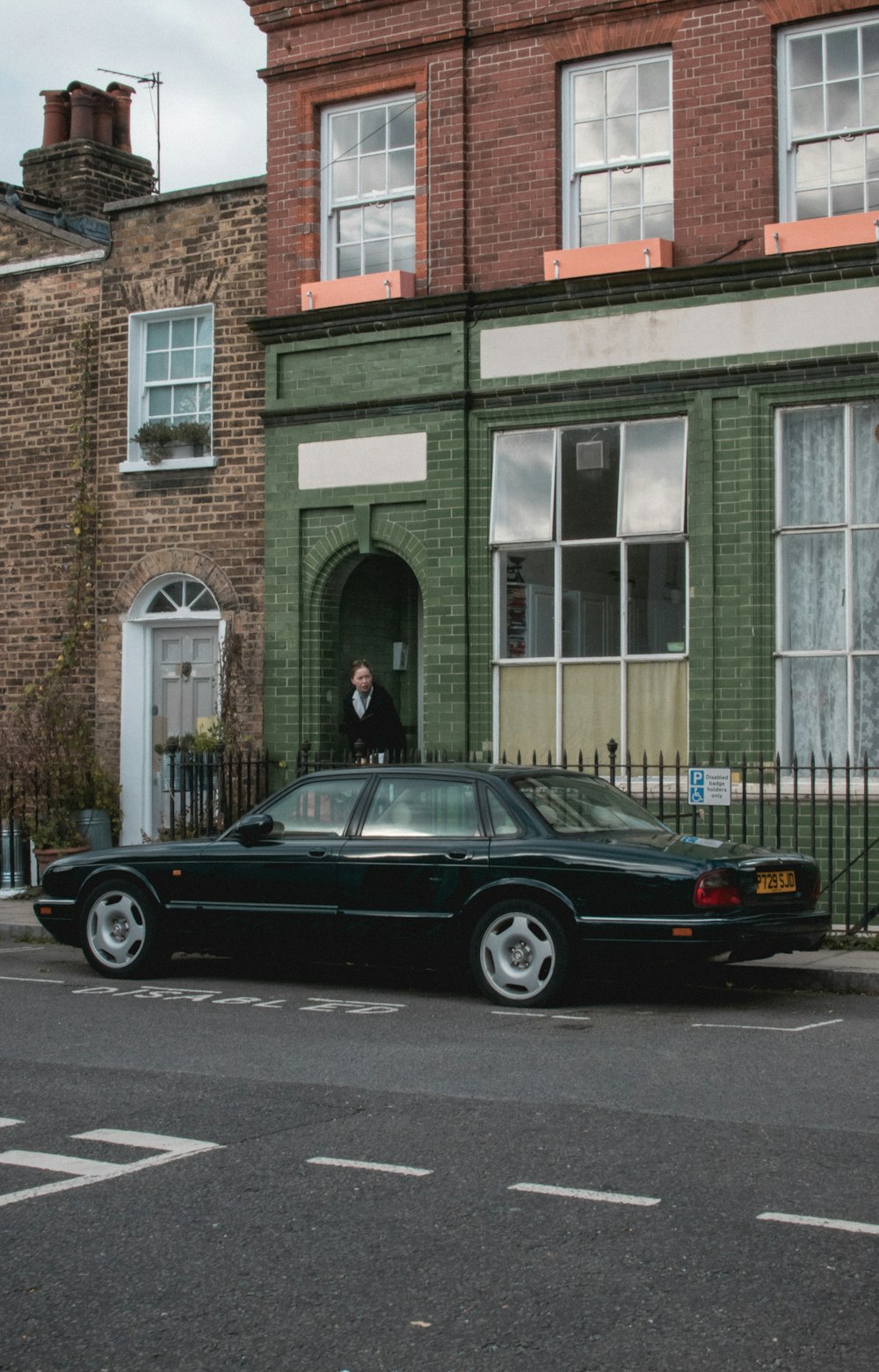 black sedan beside black fence