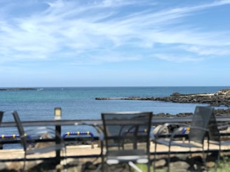 A serene coastal porch with wicker chairs, soft blue cushions, and a view of the ocean horizon.
