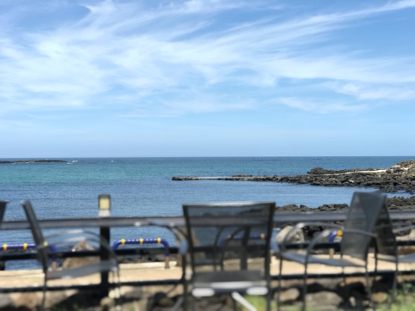 A serene coastal porch with wicker chairs, soft blue cushions, and a view of the ocean horizon.