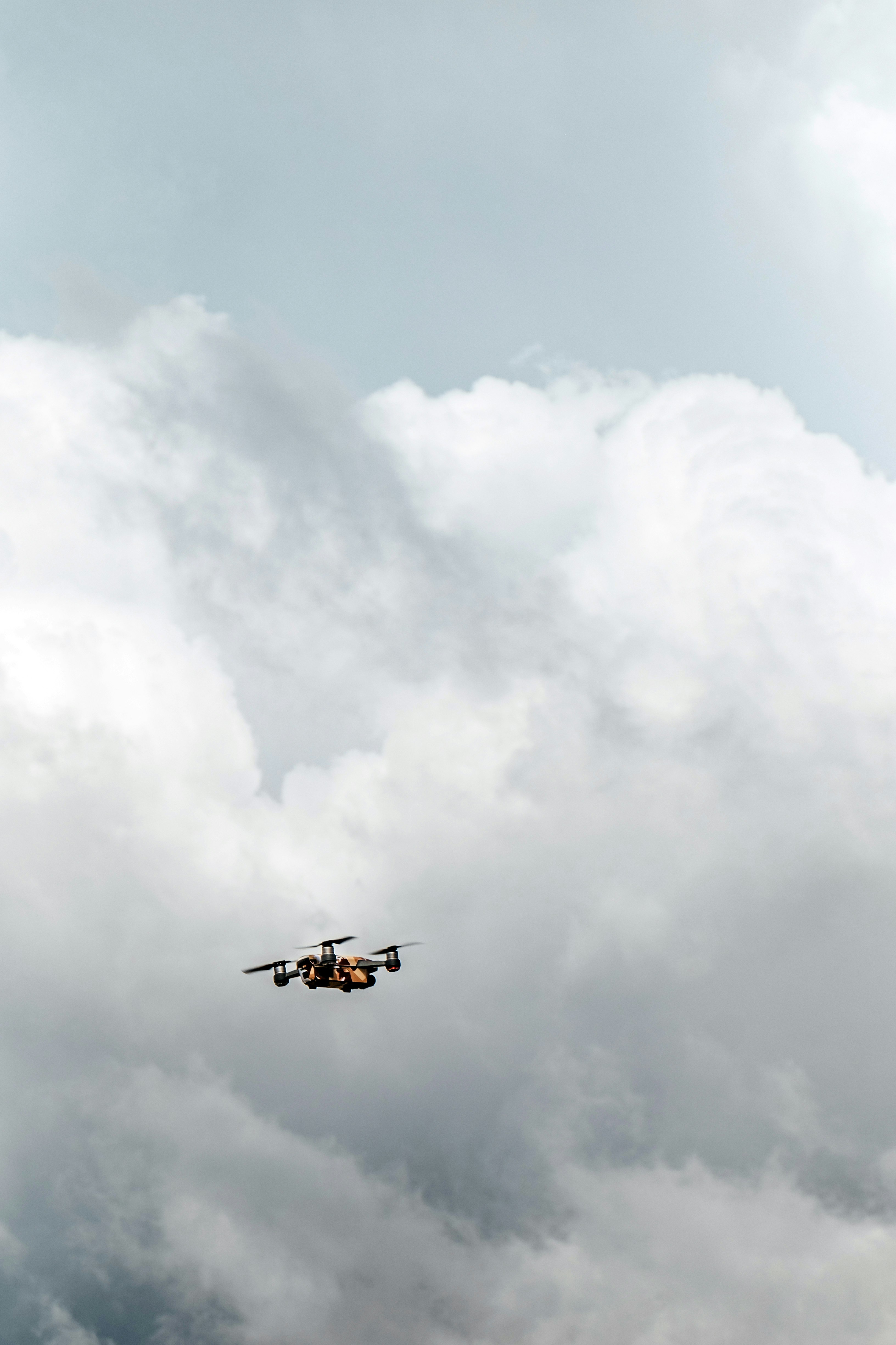 black drone under white clouds