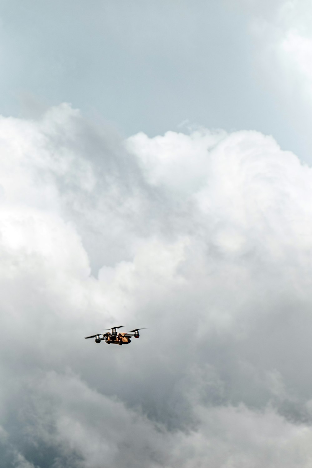 black drone under white clouds