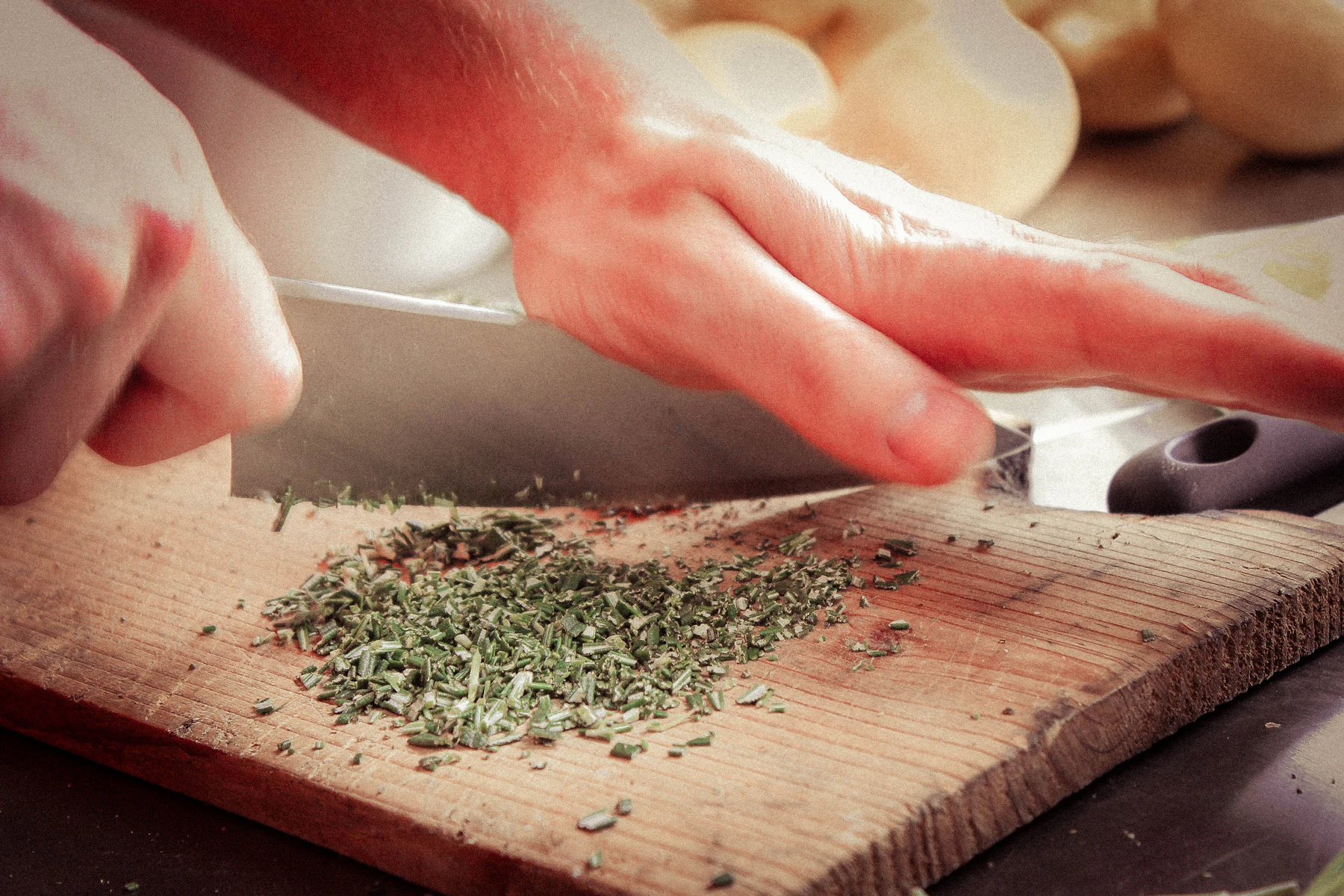 Hands chopping fresh green herbs on a wooden board