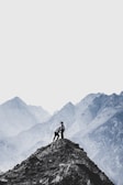 A couple standing on a mountain peak overlooking a valley.