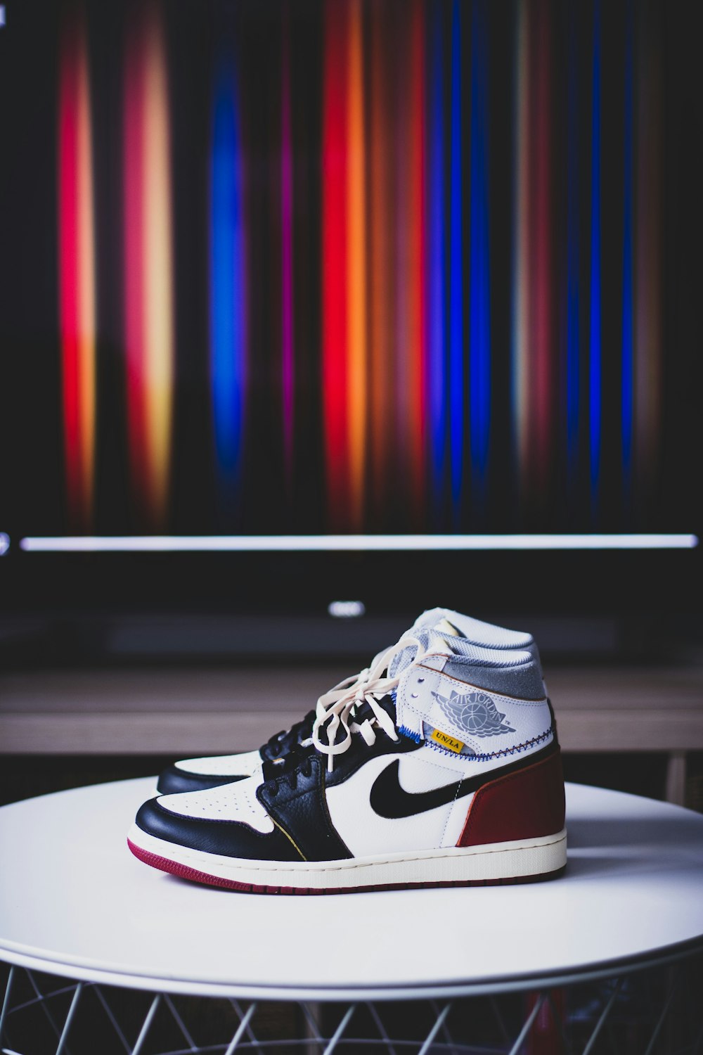 Air Jordan 1 blanco, rojo y negro sobre mesa de madera blanca