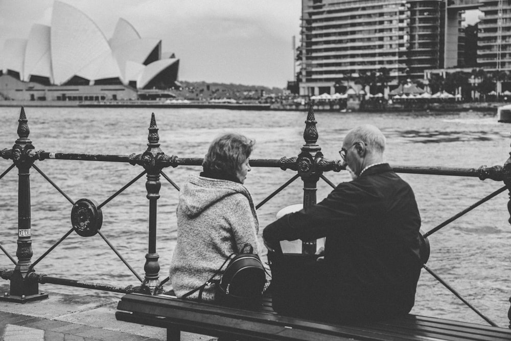 greyscale photo of man and woman sitting on bench