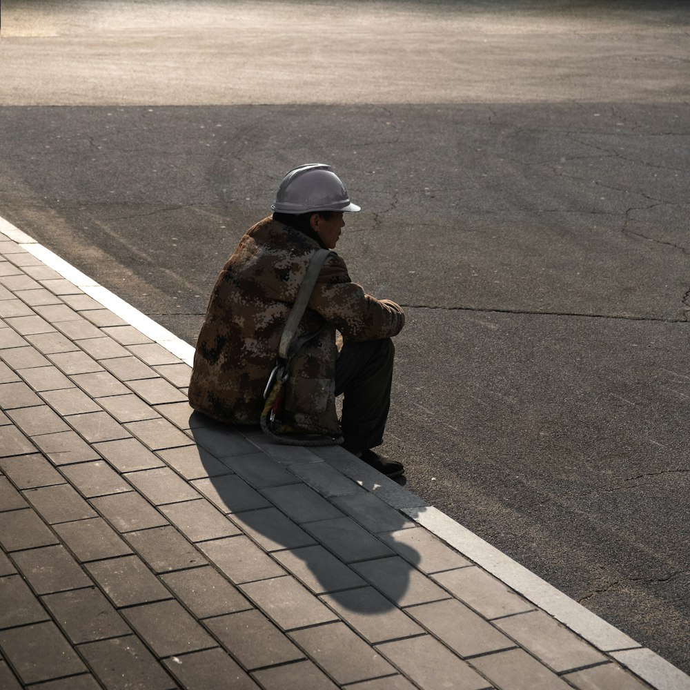 man sitting beside road