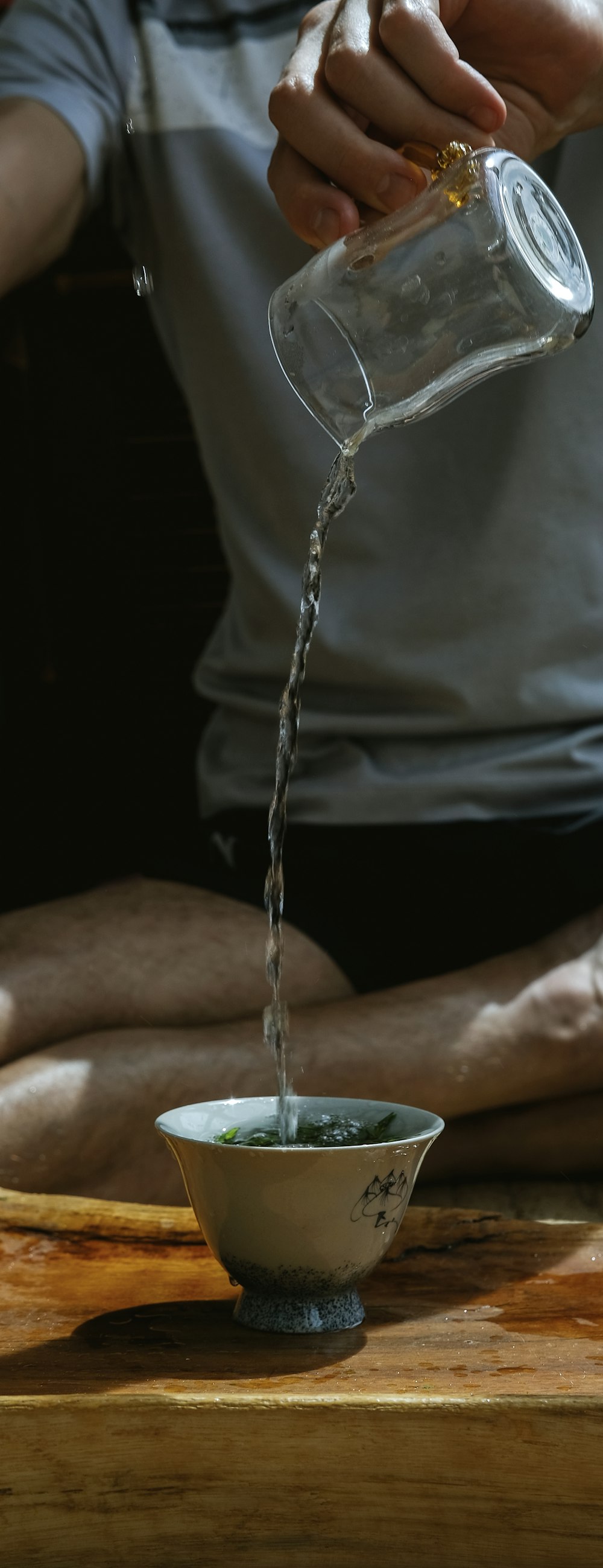 person pouring water into white ceramic mug