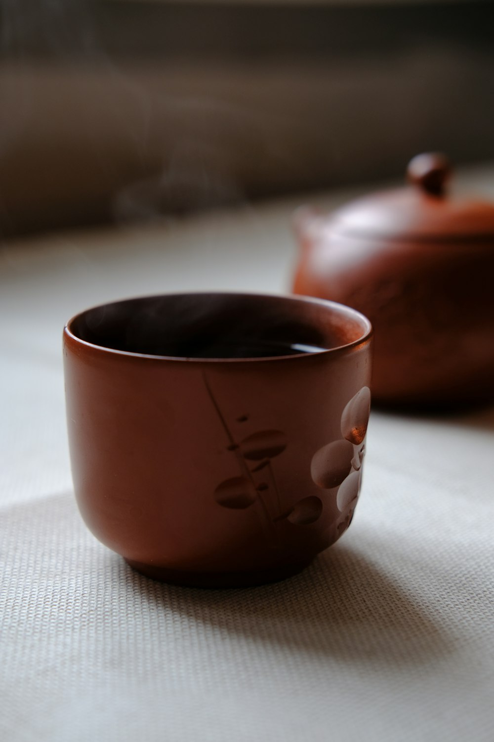 brown ceramic teacup on white textile