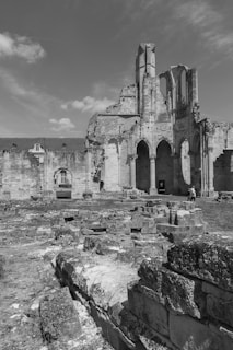 High-contrast black and white drone image of an ancient ruin site at dawn.