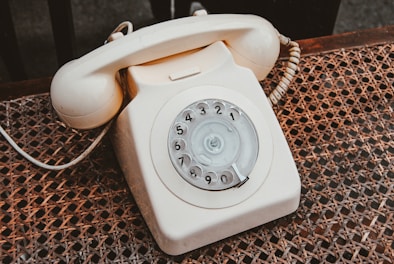 white and beige rotary telephone