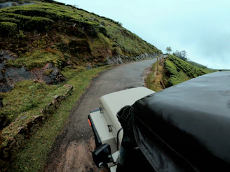 A winding road through lush hills with a vehicle cruising along.