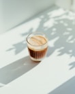 clear drinking glass with coffee on top of white table