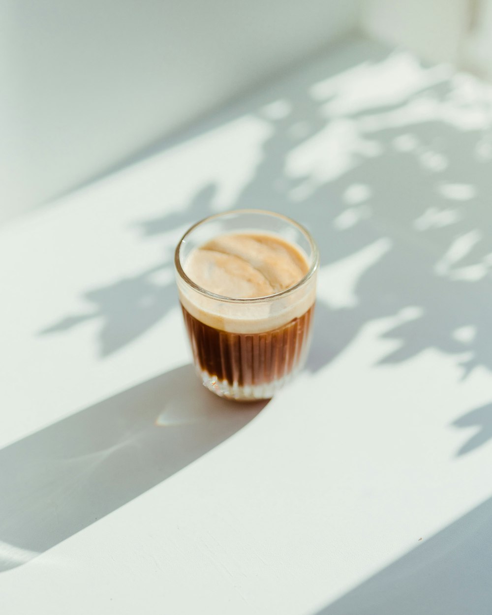 copo transparente com café em cima da mesa branca