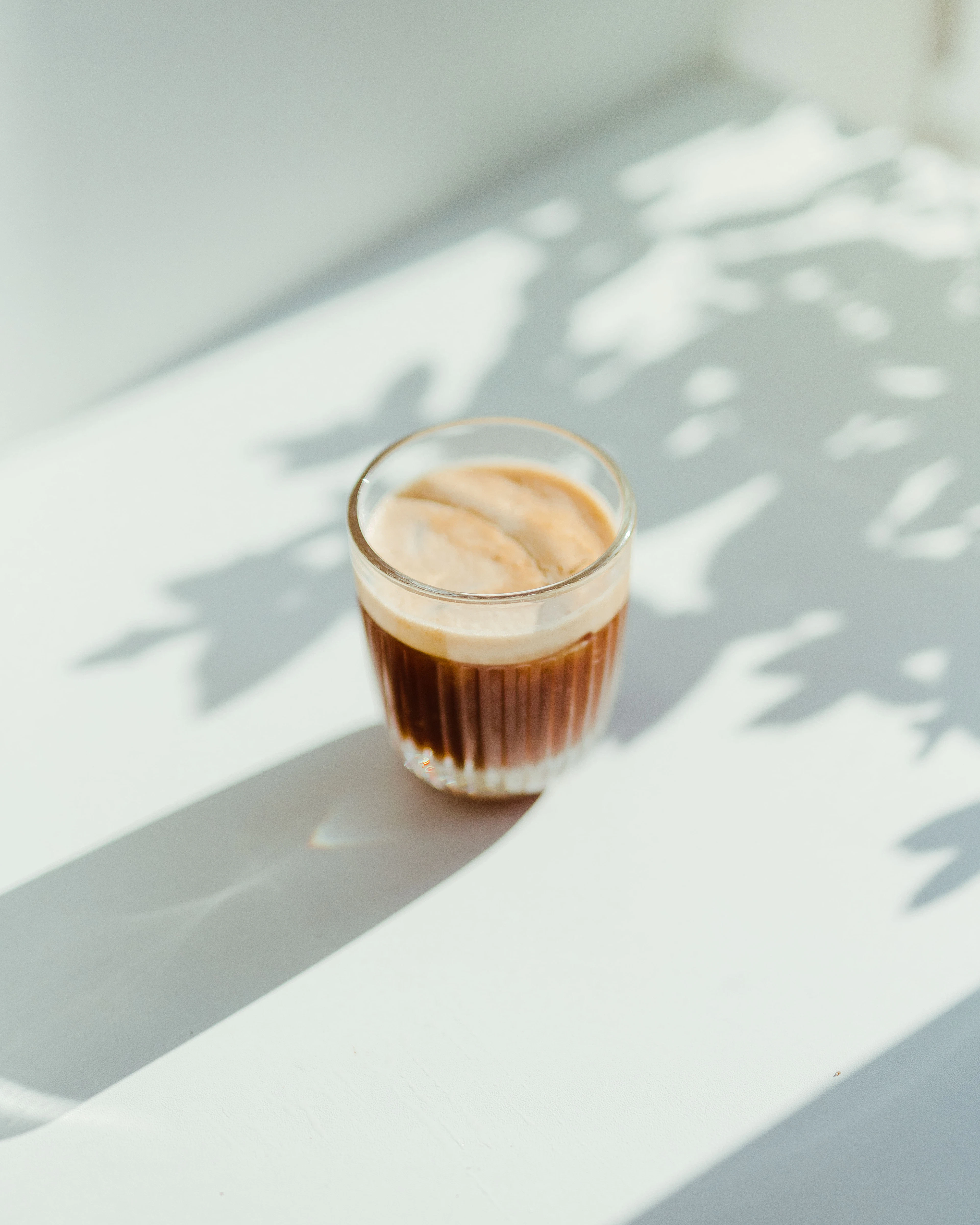 A glass of iced coffee in hard morning light