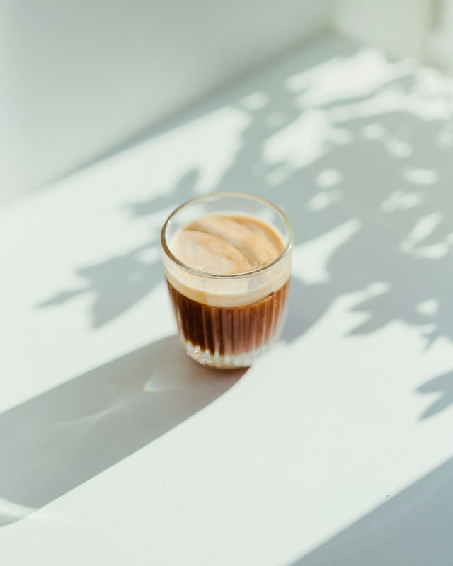 Iced coffee in a short glass under leaf shadow &mdash; stock photograph standing in for an item that has not been confirmed, not a Paradiso dish