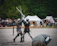 People dressed in medieval costumes competing in a lively outdoor tournament.
