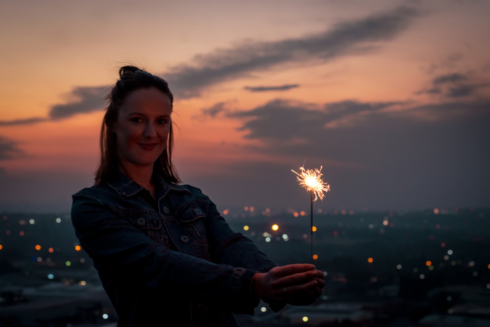 Frau steht und hält eine brennende Wunderkerze in der Hand