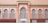 A facade with ornate architectural details features arched windows fitted with intricate white wrought iron grilles. The wall is painted in a warm peach hue, while the roofline is accented by vibrant green tiles.