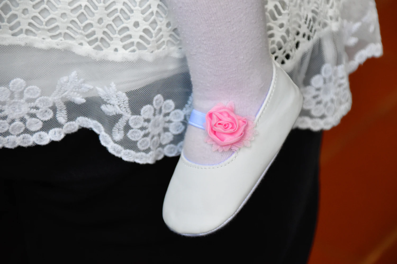 Close-up of a child's white princess shoe with a soft pink flower detail