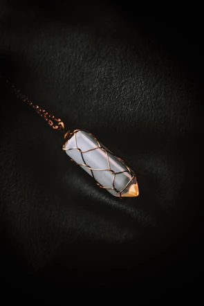 A dramatic necklace featuring sharp, pointed arches reminiscent of cathedral windows, displayed on a stone pedestal.