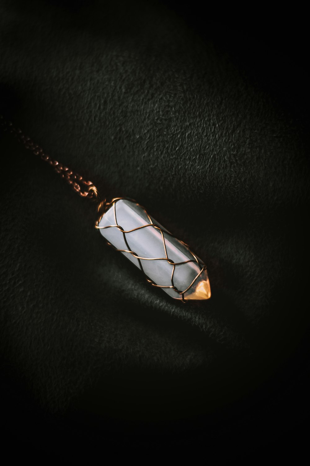 a white stone pendant on a gold chain