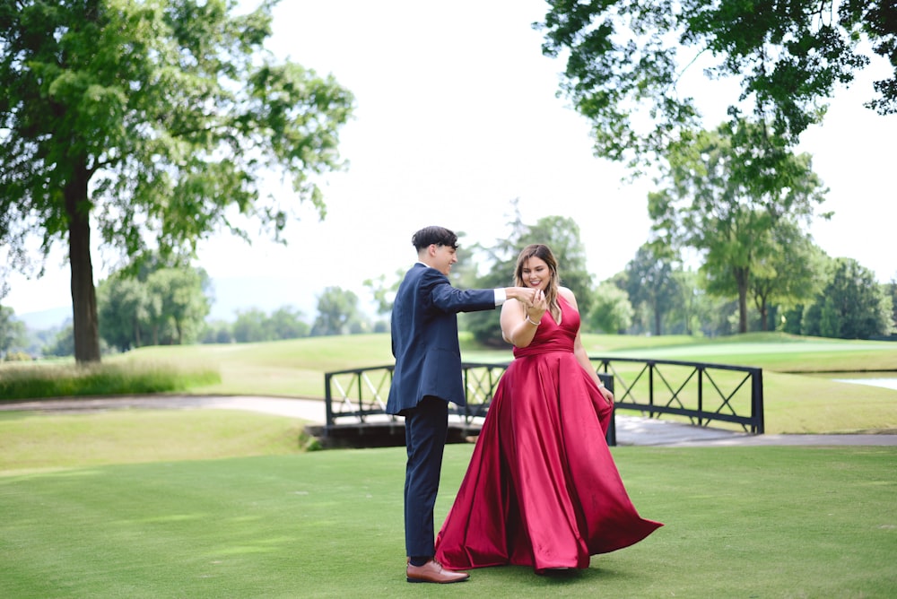 man in grey suit dancing with woman wearing pink dress outside