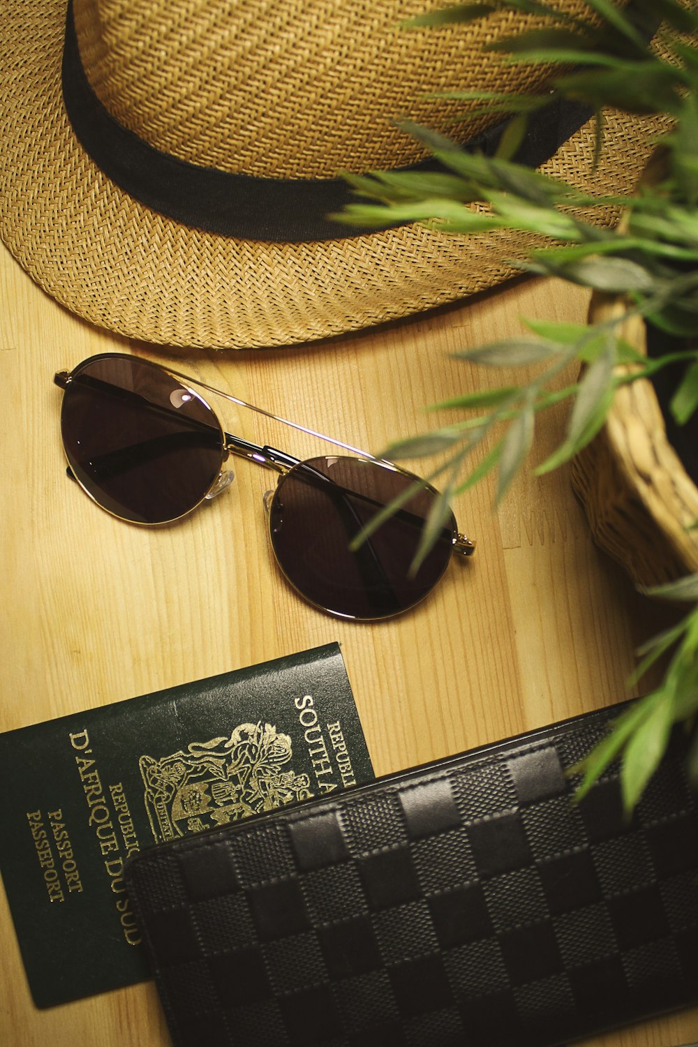 black Louis Vuitton leather wallet beside passport and sunglasses