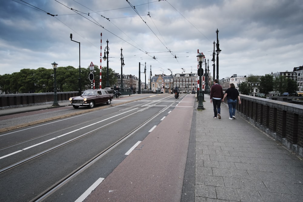 two persons walking along sidewalk of bridge